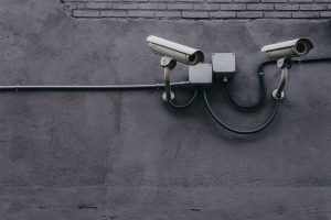 A dark wall with security cameras connected to a wire. 
